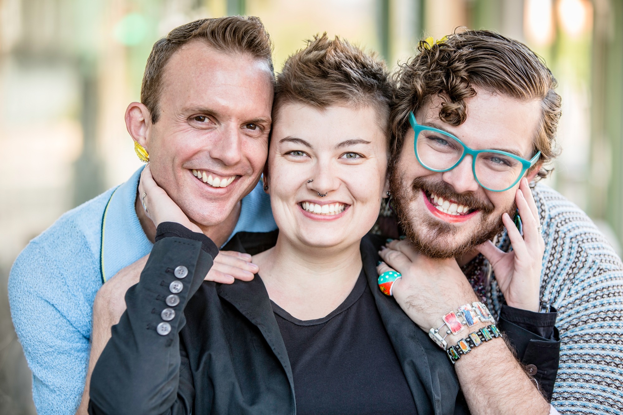 Three gender fluid friends pose and smile.